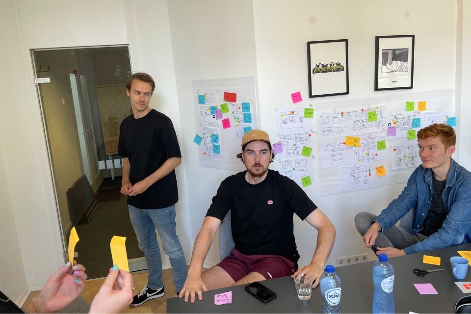 Design sprint bord met drie mensen aan tafel daarvoor.