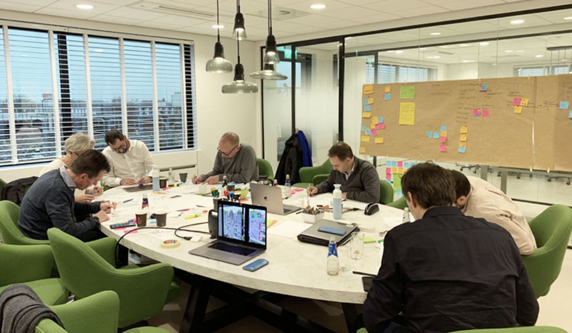 Mensen aan een grote ronde tafel aan het werk tijdens een design sprint.